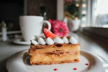 Millefeuille Napoleon with coffee in cafe. Exquisite dessert with fresh berries on white background. French Vanilla Raspberry Mille-feuille on the dish
