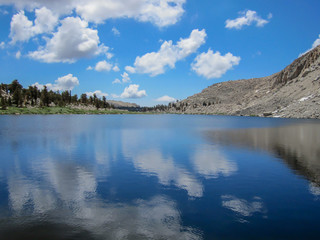 Placid lake in high sierra nevada mirroring deep blue sky and clouds