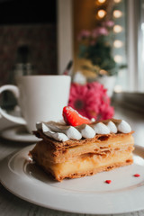 Millefeuille Napoleon with coffee in cafe. Exquisite dessert with fresh berries on white background. French Vanilla Raspberry Mille-feuille on the dish