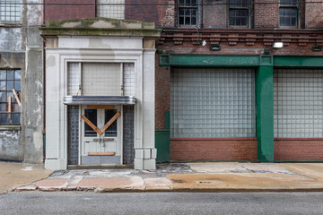 Boarded up entrance to an abandoned factory with classic architectural entrance