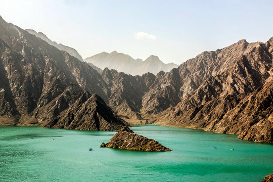 Geological landscape of hatta dam characterised by dry and rocky mountains and lake between scenery mountains, water reservoir Between hills in Dubai, United Arab Emirates