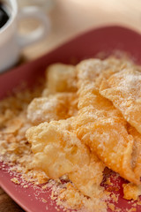 Dessert. Crackled crispy cookies with sugar on a plate and a cup of coffee on a wooden table. Blurry background and soft focus. Close-up.