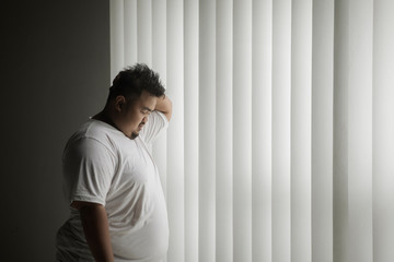 Fototapeta na wymiar Overweight man looks lonely near the window