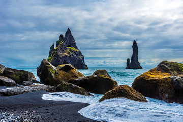 Reynisdrangar  basalt sea stacks  viewed from Reynisfjara beach seashore. Atlantic Ocean coast of Southern Iceland.