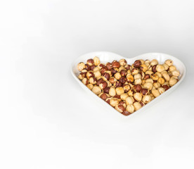 Nuts arranged in heart  on background. Healthy Food image close up hazelnuts. Love Texture on white grey table top view