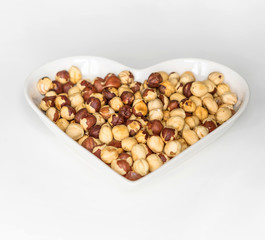 Nuts arranged in heart  on background. Healthy Food image close up hazelnuts. Love Texture on white grey table top view