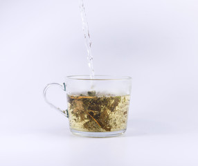 pouring hot water to the glass cup with tea, isolated on white background