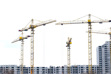 High-rise building crane with a long arrow of yellow color on a white background above a concrete building under construction with brick walls