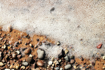 sea ​​white foam and seashore pebbles on a summer day