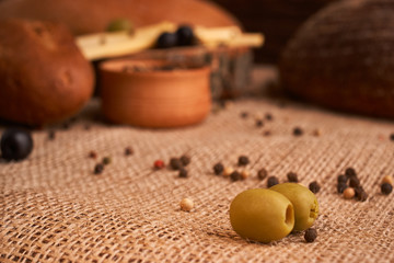 olive is on the table in background of bread, baguette and cheese. Selective focus