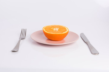 half an orange on a plate isolated on white background
