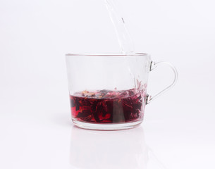 Pouring hot water to the glass cup with hibiscus tea, isolated on white background