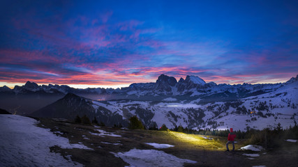 Single Hiker with headlight under purple sky before sunrise in Mountain village Seiser Alm, Italy