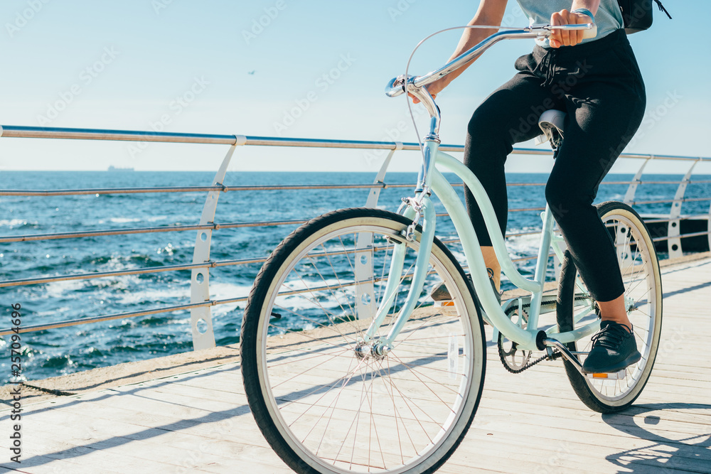 Wall mural young woman riding vintage bike along the waterfront