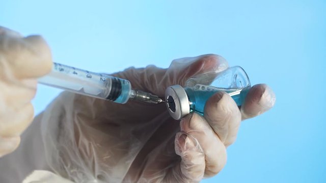 Filling medicine from ampule into syringe a blue medicine