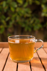 Cup of green tea on wooden table outdoors