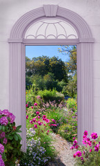 Blick durch einen Torbogen auf bunte Sommerblumen im Park