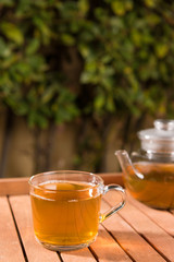 Teapot of green tea on wooden table outdoors