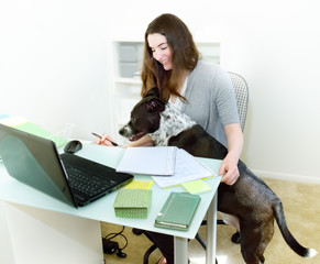 Businesswoman tries to work with dog interference in office