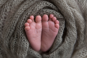 Fototapeta na wymiar the legs of a newborn baby in his hands . baby's feet. baby feet on khaki background