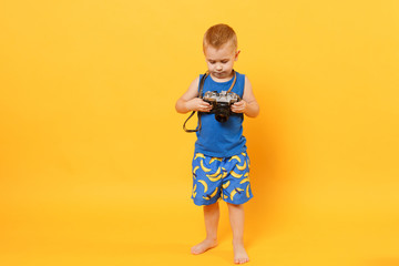 Kid boy 3-4 years old in blue beach summer clothes hold retro camera isolated on bright yellow orange wall background children studio portrait. People childhood lifestyle concept Mock up copy space.