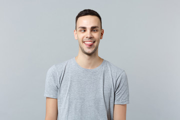 Portrait of crazy loony funny young man in casual clothes with beveled eyes showing tongue isolated...