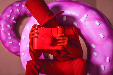 Stylized fantasy red photographer in scenic make-up with camera.