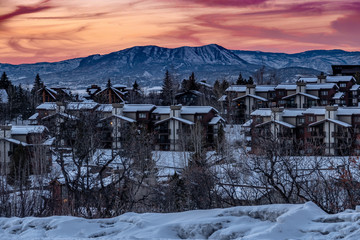 Snow covered condominiums at sunset, near the ski slopes of the Steamboat Springs Resort, in the Rocky Mountains of Colorado.  A mountain peak known as the Sleeping Giant, is seen in the background. 