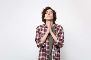 Portrait of pleading young man in casual clothes looking camera, folded his hands, praying isolated...