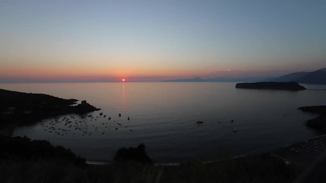 San Nicola Arcella, Cosenza, Calabria, Italy - September 4 2018: sunset time lapse on the Crawford tower (Watchtower) with boats in the bay on the Mediterranean Sea