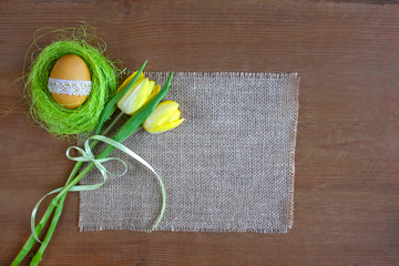 Wielkanocne tło - żółte pisanki i żółte tulipany na tkaninie z juty