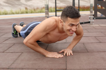 Fototapeta na wymiar Healthy Lifestyle. Young man exercising outdoors doing push ups smiling cheerful close-up