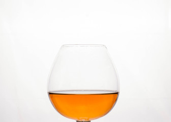 close up of half filled cognac glass with brown beverage isolated on white 