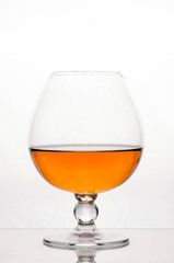 half filled cognac glass with brown beverage isolated on white 