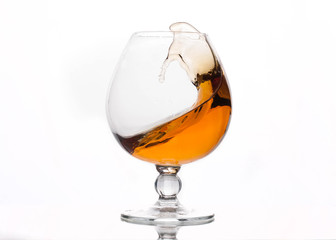 splash of scotch in transparent glass with reflection isolated on white 