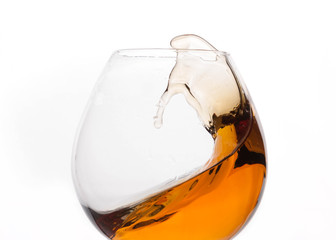 close up of splash of brown whiskey in transparent glass isolated on white 