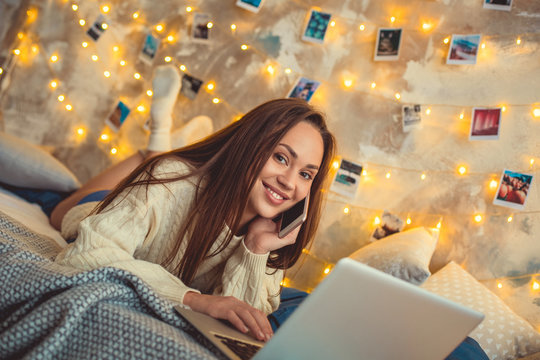 Young woman weekend at home decorated bedroom talking by smartphone