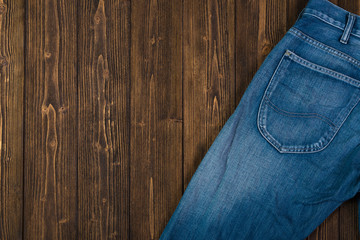 Frayed jeans or blue jeans denim collection on rough dark wooden table background, top view with copy space, old fashion concept.