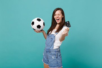Cheerful blinking young woman football fan support favorite team with soccer ball, credit bank card...