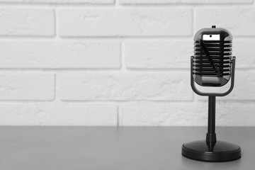 Retro microphone on table near brick wall. Space for text