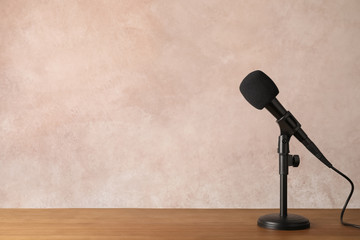 Modern microphone on table against color background. Space for text