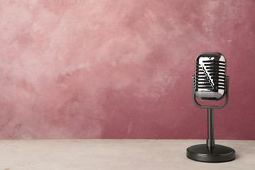 Retro microphone on table against color background. Space for text