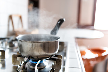 Closeup of vintage tiled gas stove top with tiles white countertop and stainless steel pot and...