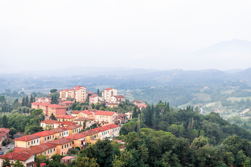 Fototapeta na wymiar Chiusi village cityscape in Tuscany Italy with orange red rooftop tile houses on mountain countryside and rolling hills with morning mist haze fog