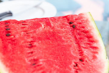 Summer day with vivid vibrant colorful red watermelon half cut outside seeded black seeds