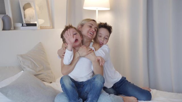 Happy family - mother with two sons hugging in bed