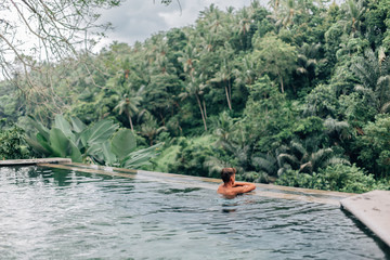Human swimming in Bali infinity pool