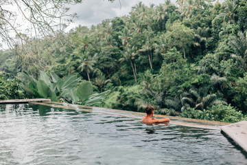 Fototapeta na wymiar Human swimming in Bali infinity pool