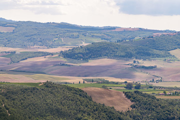 Naklejka premium Val D'Orcia countryside aerial high angle view in Tuscany, Italy with rolling plowed brown hills with farm landscape picturesque meadow fields