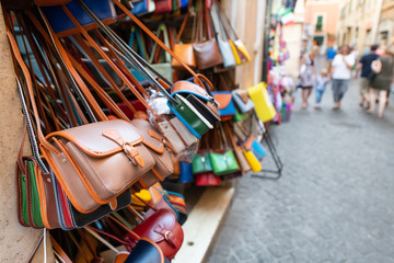 Rome, Italy many leather purse bags vibrant colors hanging on display in shopping street market in...